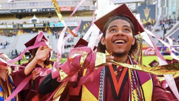 A student at ASU graduation looks up as confetti falls at the end of the ceremony
