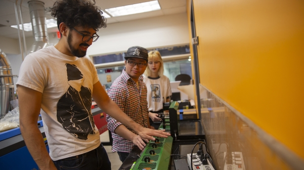 Three students work with the 3D printing plastic recycling tool.