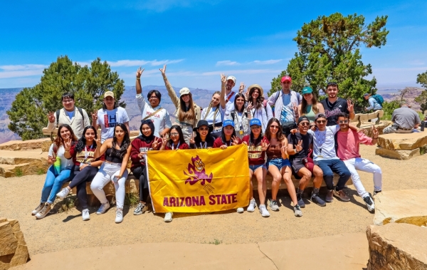Group of students gather around an ASU banner at the Grand Canyon.