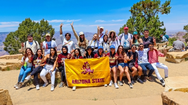 Group of students gather around an ASU banner at the Grand Canyon.