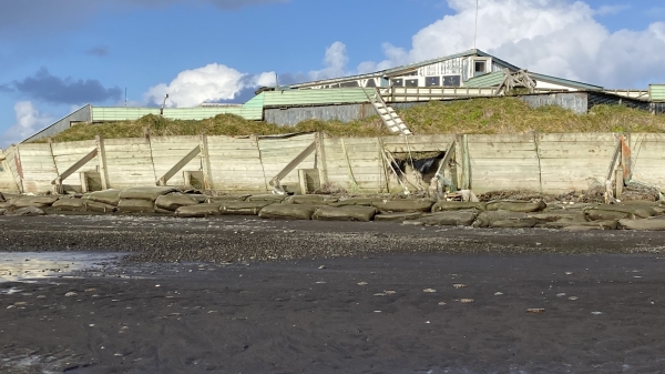 A view of seawalls reinforced with sandbags, as seen from the ocean looking toward the land.