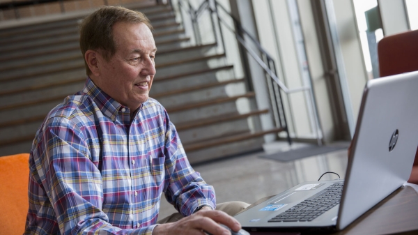 Photo of man sitting in front of a laptop. 