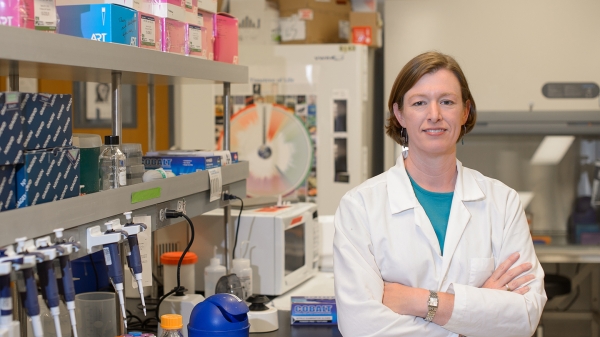 ASU Regents Professor Anne Stone in a white coat in a lab.