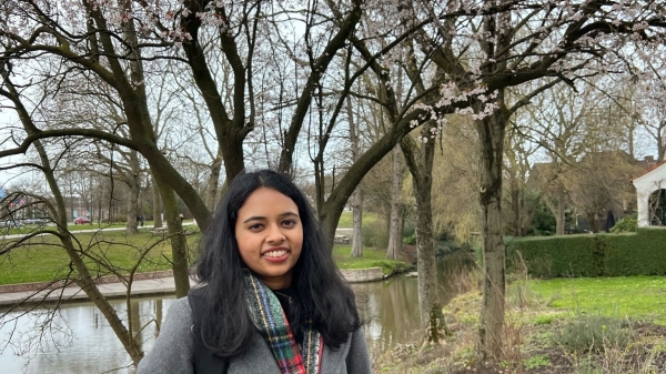 Anusha Natarajan is photographed standing in front of a tree wearing a warm jacket.