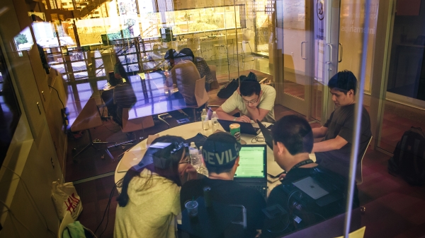 Students work around a table at a hackathon