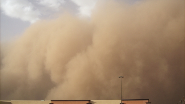 A towering cloud of dust moves through a desert city