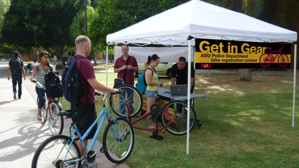 Students and their bicycles surround an outside tent.