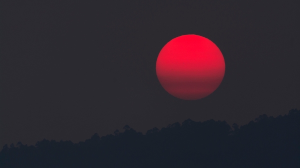 Blood moon over a mountain at night