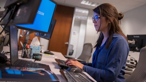 An intern works at a computer in an office.