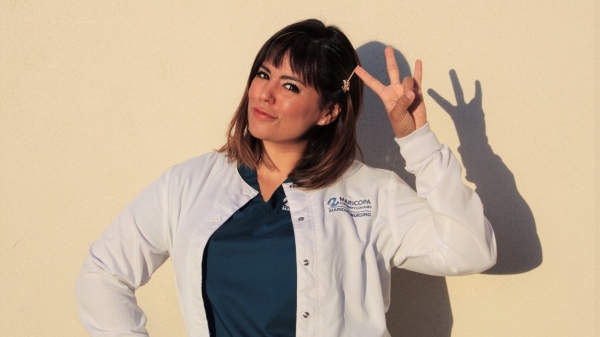 ASU Online Student Claudia Becerril poses in her nursing school scrubs and throws the pitchfork
