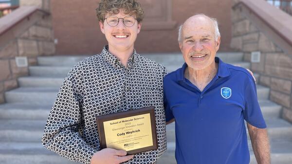 Student posing with donor holding award