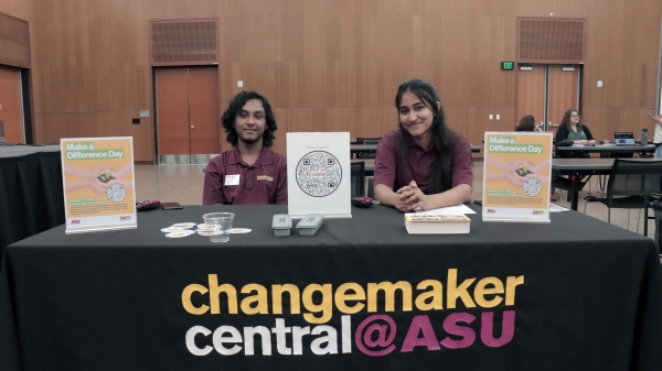 Two students seated at a table with a sign that reads "Changemaker Central @ASU"