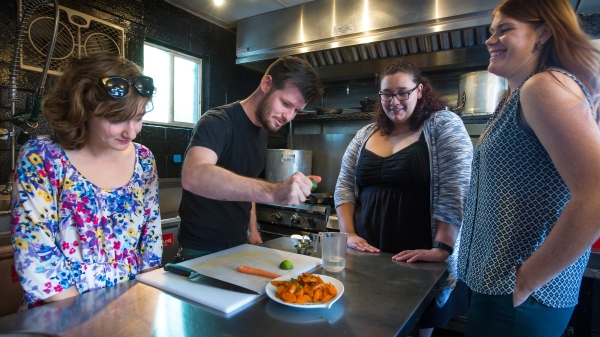 Students and a chef in a kitchen.