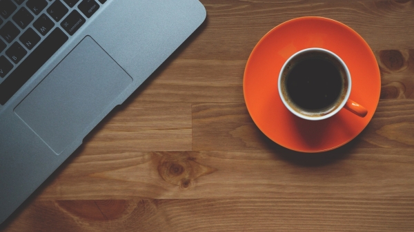 A cup of coffee next to a laptop