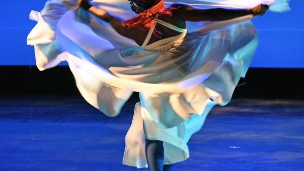 Woman dancing in a white dress as it twirls around her body.