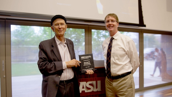 Photo of two men standing with one holding a plaque.