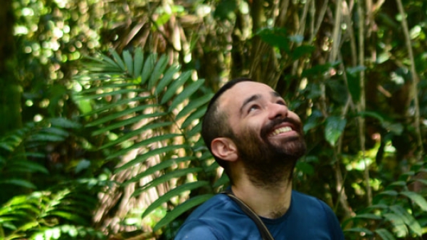 ASU researcher Sebastían Ramírez Amaya smiling and gazing upward in a forest setting.