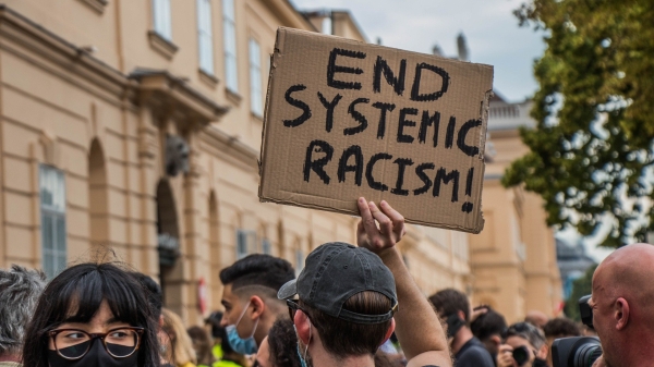Picture of a protest sign help up that reads end systemic racism!
