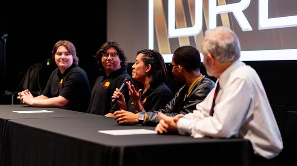 Five people sitting at a table having a discussion.