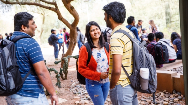 Students smile and talk outside