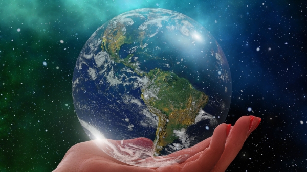 An image of a human hand holding the planet Earth in space.
