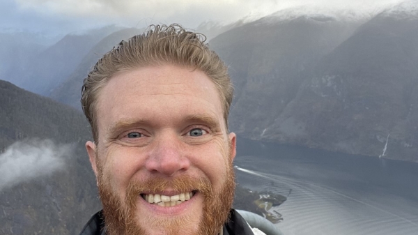Nick Heier smiling with mountains and water in the background