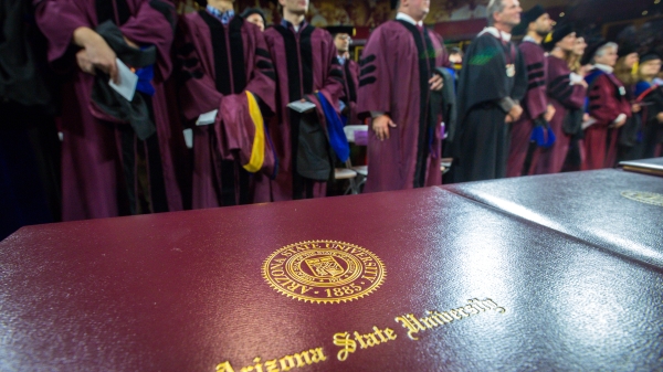 diplomas with graduates in the background