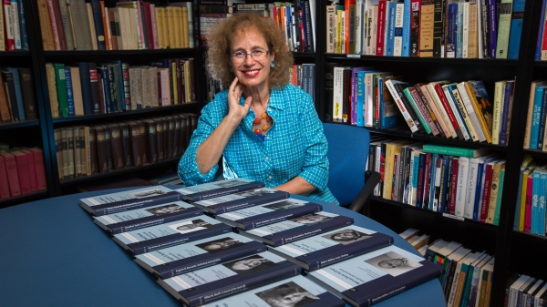 woman sitting in office with volume of books on table