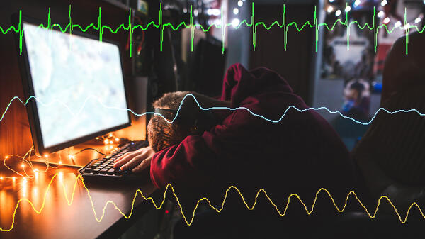 Gamer with head down in front of desktop overlaid with heart monitor line graphs