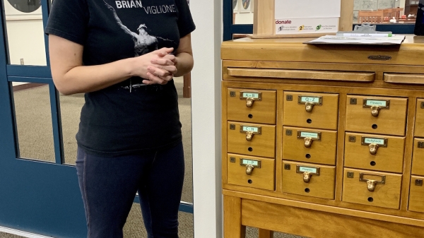 Christina Sullivan stands next to the card catalog housing the seed library