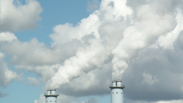 Two smokestacks release smoke into the sky.