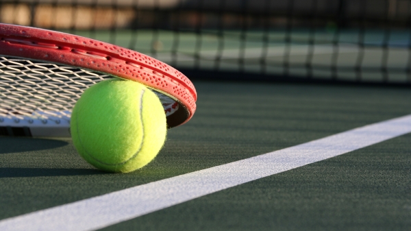 Close-up of a tennis ball and racket on a court.
