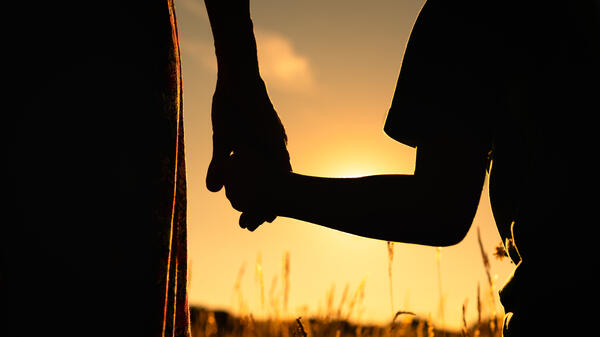 Silhouettes of a mother and child holding hands.