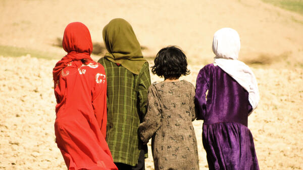 Four Afghanistan girls walking in the mountains, facing away from the camera.