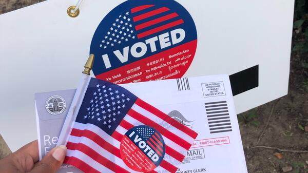 Hand holding papers with stickers that read "I voted."