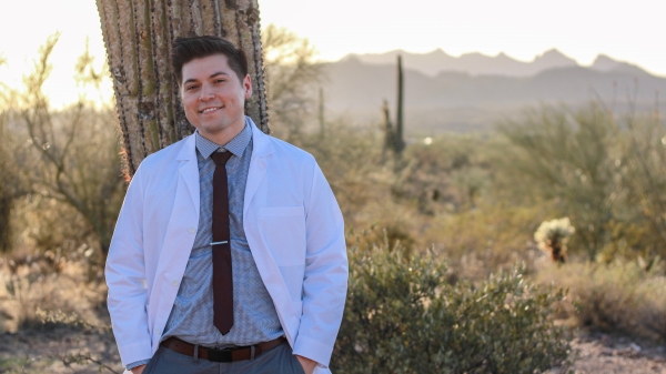 ASU doctor of nursing practice graduate Reynaldo Kieser poses in his white NP coat