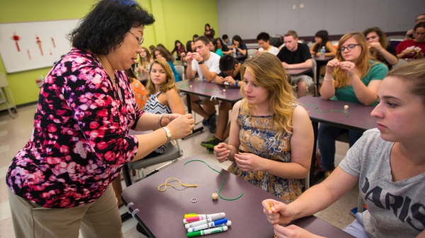 woman helping student make keychain