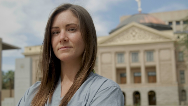 ASU Alumna and ICU nurse Lauren Leander poses in blue scrubs outside of the Arizona State Capital Building