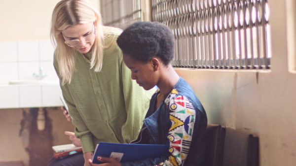 Rachel Thompson wears a green top and glasses as she talks with a student in a patterned shirt in a classroom on campus in Malawi.