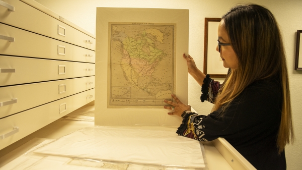 Program for Transborder Communities Program Manager Mara Lopez shows one of the historic maps that will be displayed in the newly-curated exhibit at the School of Transborder Studies.