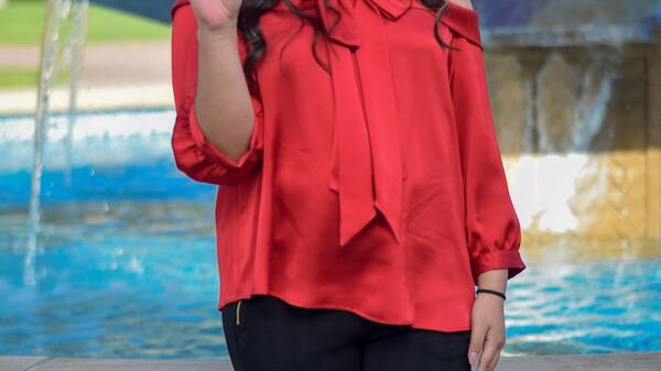 ASU grad Maricruz Santoyo giving a forks up hand symbol by the Old Main fountain