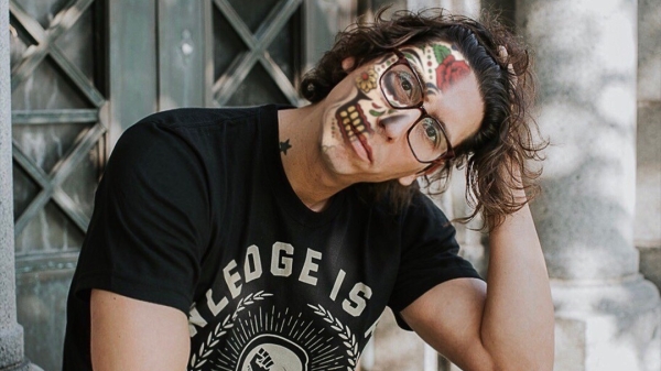 Mathew Sandoval wearing Day of the Dead face paint and sitting on a step.