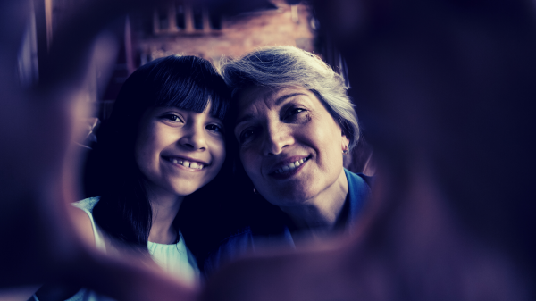 A young girl and her grandma smile at the camera