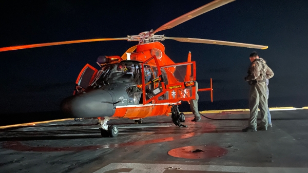 Coast Guard helicopter with a person standing next to it.