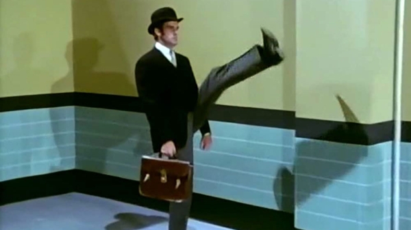 An actor does the silly walk from Monty Python's Flying Circus, with one leg kicked crazy high