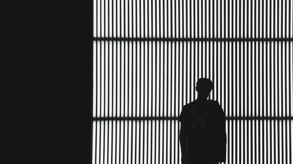 Stock photo of a person's silhouette against a backdrop of iron bars.