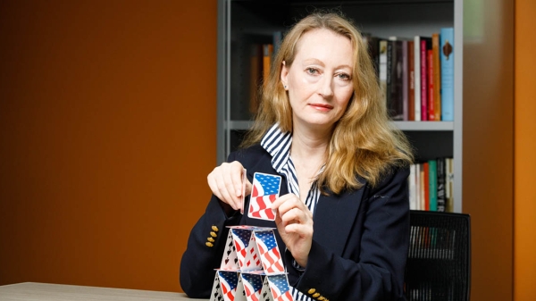 Nicole Anderson, director of The Institute for Humanities Research at Arizona State University builds a house of cards with playing cards featuring an American flag design.