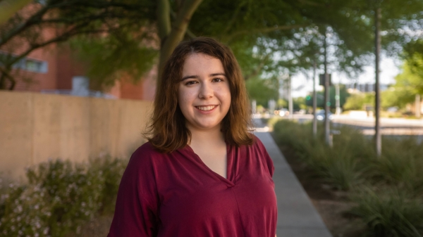 Portrait of Megan Nelson, an undergraduate student in the ASU Department of Psychology. Nelson stands on a sidewalk under a tree. She has shoulder-length brown hair and wears a burgandy blouse while smiling at the camera.