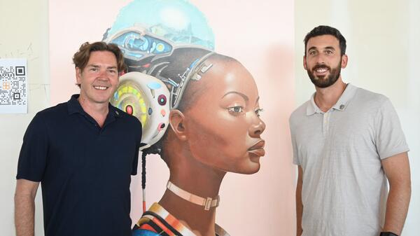 Artist James Angel and College of Health Solutions Professor Chad Stecher at Phoenix Bioscience Core art exhibition standing in front of an art piece depicting a woman's facial profile.