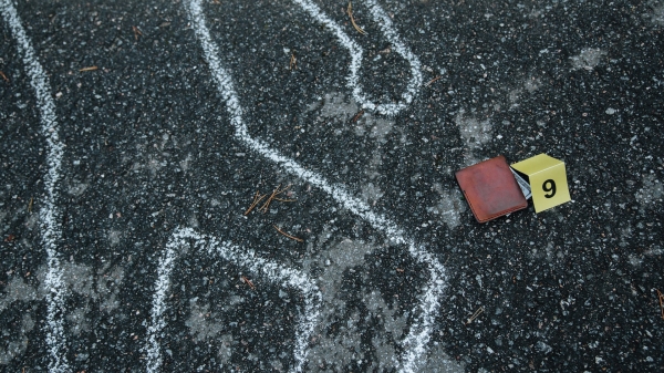 Chalk outline on pavement with number tag and wallet next to it